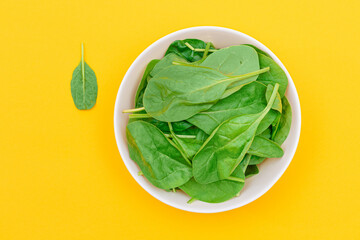 Fresh Baby Spinach Leaves in White Bowl on Yellow Background - Top View. Vegan and Vegetarian Culture. Raw Food, Green Leaves. Healthy Diet