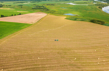 Aerial View Tractor Collects Dry Grass In Straw Bales In Wheat Field. Special Agricultural Equipment. Hay Bales, Hay Making.