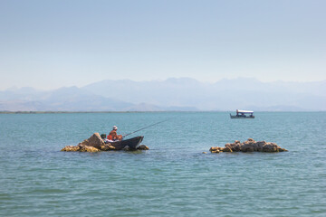 A fisherman on a motor boat catches a fish. Montenegro.