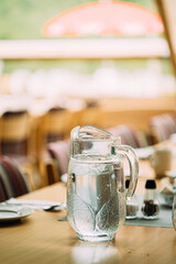 Cozy Interior Of Summer Cafe. Jug Of Icy Cold Ice Water On Table And Cutlery Laid Out