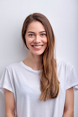 Happy cheerful caucasian woman smiling at camera, having perfect toothy smile, wearing white casual t-shirt, posing, isolated on white studio background. Copy space. People lifestyle concept