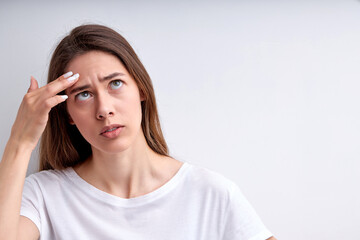 Fototapeta premium Remove acne, pimple or blemishes on beauty woman face. female looking at acne or pustules pimple. Acne occur from hormonal change. Unhappy woman isolated on white studio background, copy space