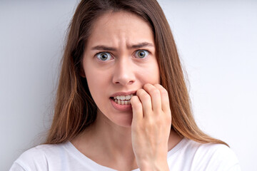 Fototapeta premium Portrait of worried surprised caucasian woman keeping hands on mouth, concerned, isolated over white studio background. People face expressions and reaction concept. Nervous female at a loss