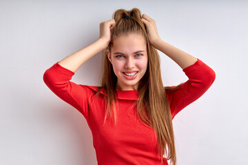 Portrait of beautiful teenage girl touching head isolated on white background, young girl in red shirt smiling, looking at camera, copy space. human emotions, happy life, people lifestyle concept