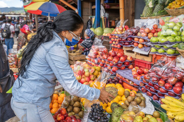 latin woman buying fruit in market. Woman choosing fruit in sale
