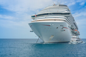 Fototapeta na wymiar White cruise ship anchored with tender ship moving passengers to shore