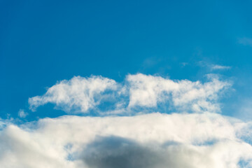 fluffy gentle clouds slowly and hopelessly float across the endless sea of blue sky. Clear blue sky after the raging elements and storms.