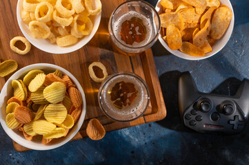 Delicious traditional set of video game players and sports fans - beer, snacks, chips, onion rings. There is also a video game joystick on the table. Video game in the company of friends, rest.