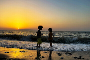 Fototapeta na wymiar Two happy kids playing in the sea at sunset