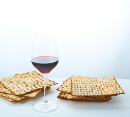 Matzah and a glass of red wine on a plain white background. Symbols of the Jewish Passover. Religion, traditions, rituals, Torah. There are no people in the photo. There is a place to insert.