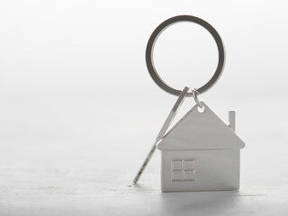 House key on a keychain in the form of a house on a white background - the concept of moving, renting out real estate, buying or selling a house. There are no people in the photo.