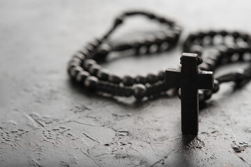 Rosary and crucifix. Black and white photo. Simple background. There are no people in the photo. Minimalism. Christianity, Catholicism, faith, spirituality, prayer.