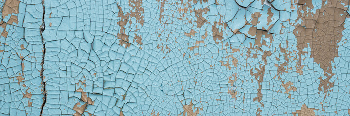 Peeling paint on the wall. Panorama of a concrete wall with old cracked flaking paint. Weathered rough painted surface with patterns of cracks and peeling. Wide panoramic texture for design background