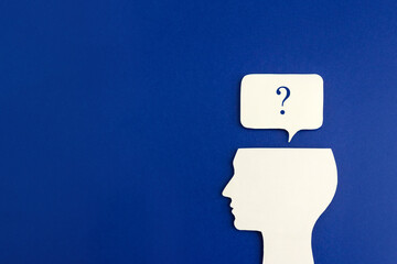 Silhouette of human head and question mark on blue background. The concept of setting problem and...