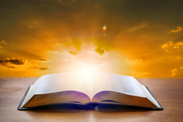 Holy Bible book on a wooden desk with sunset light background