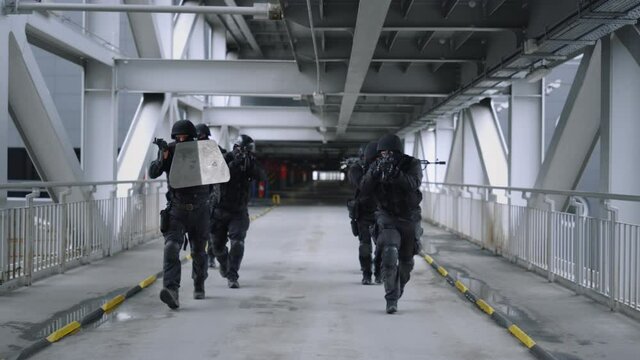 SWAT team walking on bridge. Masked military soldiers using rifles 