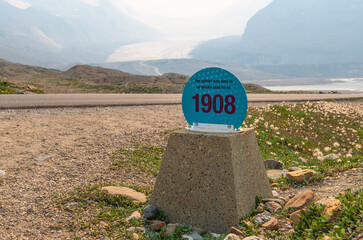 Athabasca glacier with mile post sign showing climate change effect on ice retreat since 1908, with...