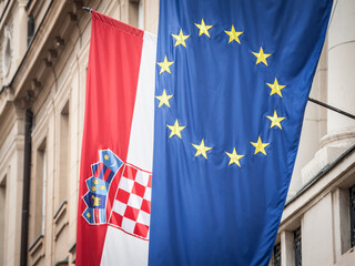 Croatian and European flags waiving in the air with a building in background. Croatia is the youngest country that joined the European Union in 2013...