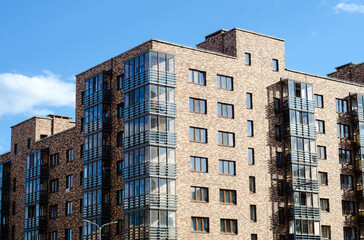 Realty.  multistorey residential building made of variegated multicolored bricks with glazed balconies.  highrise building. Multiapartment housing.