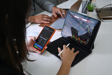 Businesswoman analyzing graph on computer tablet and using smart phone.