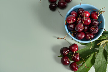 Obraz na płótnie Canvas Fresh cherries bowl on green background.
