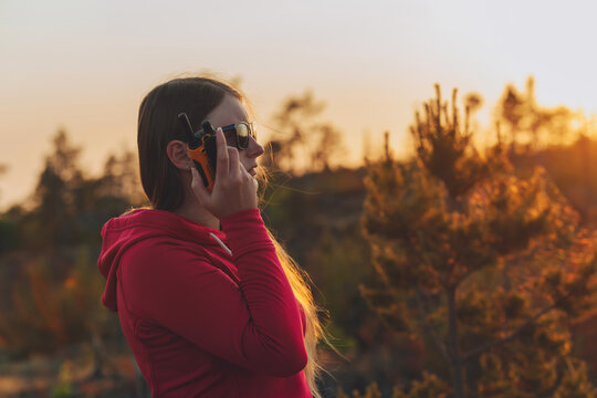 Woman Using Walkie Talkie Outdoors And Relax On Nature On Forest Background. Using Portable Handheld Radio Transceiver Outdoor. Woman With CB Radio.