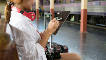 Young female using digital tablet during waiting for train at train station.