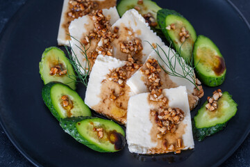 Fresh salad with green cucumber and white cheese with olive oil sauce and roasted almonds