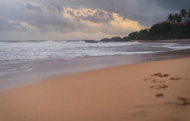 Blurry footprints on a sandy beach, scenic evening seascape in Galle. Paradise island of Sri Lanka.