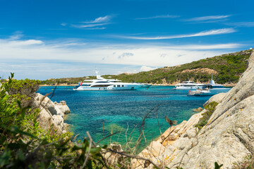 Stunning view of a bay of water with luxury yachts sailing on a turquoise water during a sunny day....
