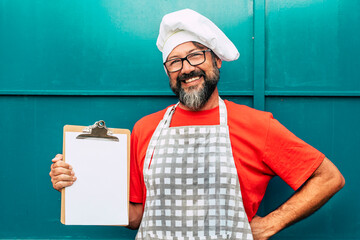 Cheerful happy man chef outside closed restaurant use a white empty board - copy space business...