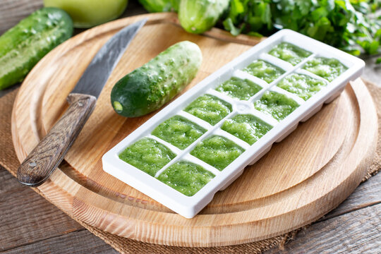Frozen cucumber puree in ice cube trays ready for freezing on a cutting board on a table. Frozen Food Concept.