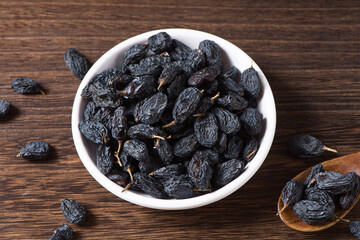 Dried fruits, pile of black raisins on table.