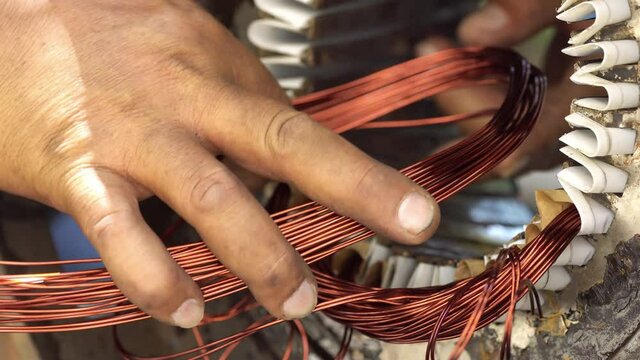 Mechanic stacks coils of the stator. Electric motor repairing.
