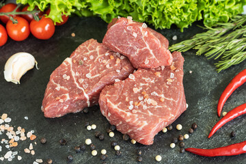 Raw fresh marbled beef meat, seasonings  on dark stone cutting board