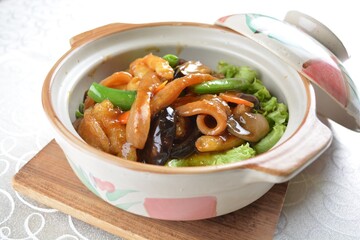 braised fish maw and sea cucumber with mixed vegetables in chicken stock in hot clay pot in white background asian halal seafood menu