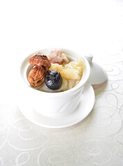 double boiled premium seafood with fish maw, black garlic, mushroom, chicken soup pot in white background asian halal seafood menu