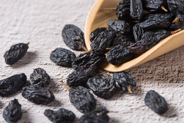 Dried fruits, pile of black raisins on table. - obrazy, fototapety, plakaty