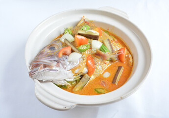 local spicy chilli curry soup big grouper fish head with vegetables in hot clay pot in white background asian halal seafood menu