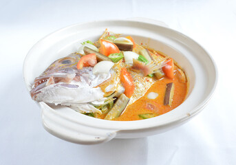 local spicy chilli curry soup big grouper fish head with vegetables in hot clay pot in white background asian halal seafood menu