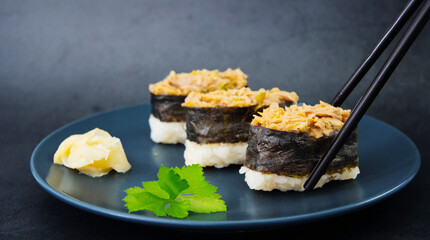 Close-up of a pair of chopsticks picking up a sushi, Japanese cuisine, black background
