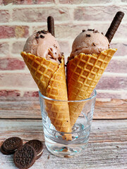 Strawberry chocolate ice-creams in a cone, chocolate sandwich cookies, brick wallpaper background