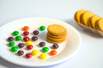 Close-up of sandwich biscuits on a white plate, colorful seasoned beans on a white table