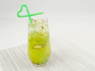 Close-up of iced kiwi juice with straw, cool and refreshing, white background