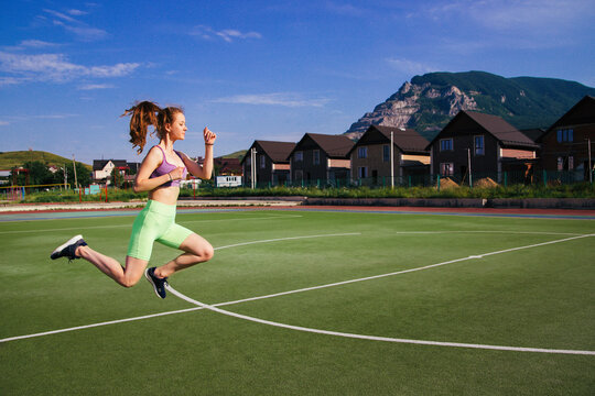 A young woman jumps on a football field. A girl at the stadium is engaged in sports.A healthy lifestyle.