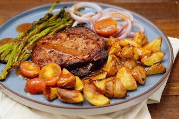 Roast pork with black pepper with potatoes, tomatoes, topped with sauce in plate