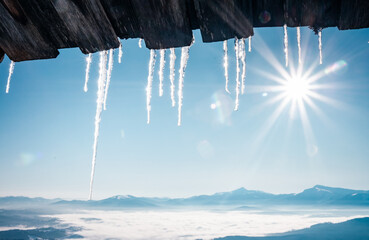 Spectacular icicles shine in sun against blue sky. Splendid view with ice icicles hanging from roof.