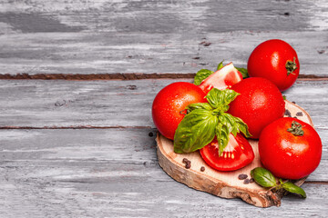 Ripe tomatoes with fresh basil leaves, black salt, and peppercorn