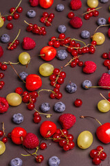 Assorted ripe berries, scattered on a black stone background