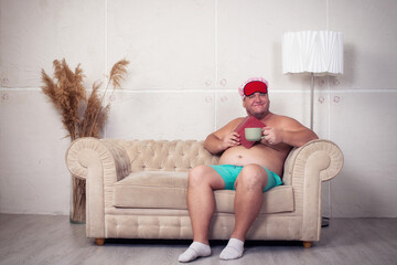 Funny fat man is resting on the sofa at home.